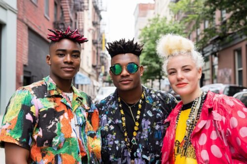 three-friends-pose-together-city-street-showcasing-colorful-styles-playful-hairstyles-1
