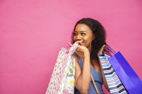 happy-young-woman-posing-with-shopping-bags-isolated-pink-wall